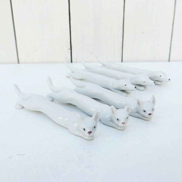 Six porte couteaux en porcelaine blanche représentant trois chiens et trois chats. A chacun sa team. Une oreille d'un chat cassée. Bon état général. Longueur : 13 cm