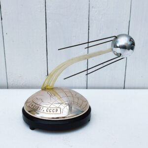 Boite à musique commémorative soviétique à remontage mécanique. Il s’agit de la chanson patriotique « Grand et vaste est mon cher pays…, et fait aussi le son typique du satellite.  Elle a été produite fin les années 1950s en édition limitée suite au lancement du premier satellite Sputnik Spoutnik. La date du lancement est gravée sur le socle de l’objet. Le blason communiste « La faucille et le marteau » est gravé sur l’engin spatial. Petites traces d'usage Bon état général. Hauteur : 16,5 cm