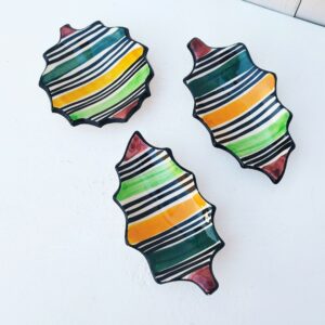 Trois coupelles en céramique de Vallauris, décor rayures de différentes couleurs. Deux coupelle en forme de feuilles, et une en étoile. Une micro égrenure sur l'étoile, un petit éclat sur le bout d'une feuille et un petit éclat sur le bout et la queue de l'autre feuille. Non visible une fois posées. Bon état général. Dimensions feuilles : 20 x 11 cm Diamètre étoile : 13 cm
