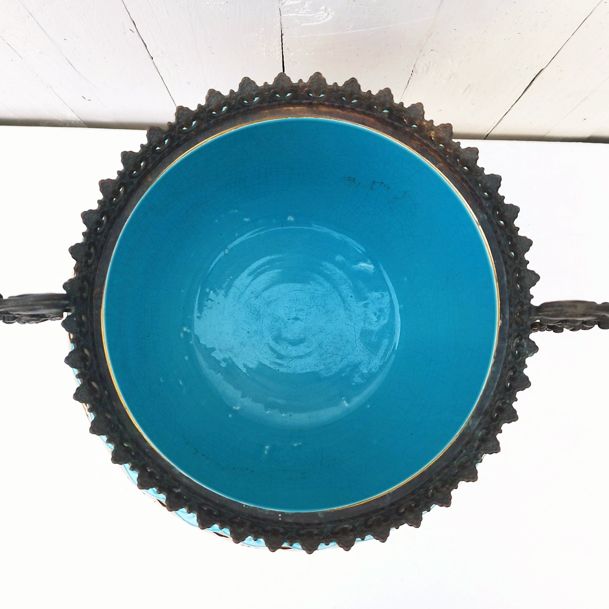 Grand cache-pot ou jardinière en céramique de Sarreguemines numéro 2048. Cerclé d'une couronne en bronze aux prises formant des lions. Pied tripodes en bronze. Couleurs bien vives. races d'usage à l'intérieur. Très bon état. Hauteur max  : 40 cm Diamètre : 25 cm