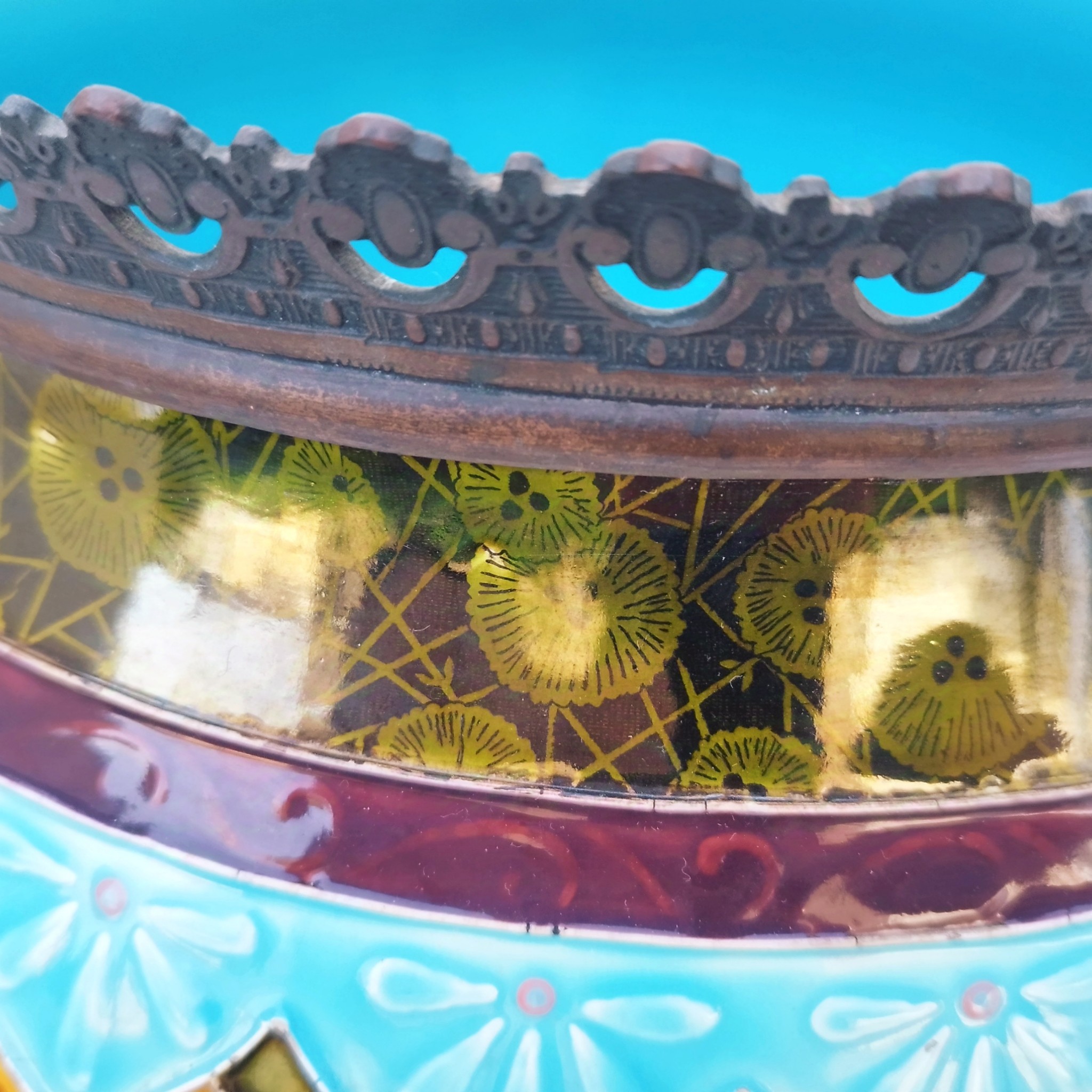 Grand cache-pot ou jardinière en céramique de Sarreguemines numéro 2048. Cerclé d'une couronne en bronze aux prises formant des lions. Pied tripodes en bronze. Couleurs bien vives. races d'usage à l'intérieur. Très bon état. Hauteur max  : 40 cm Diamètre : 25 cm