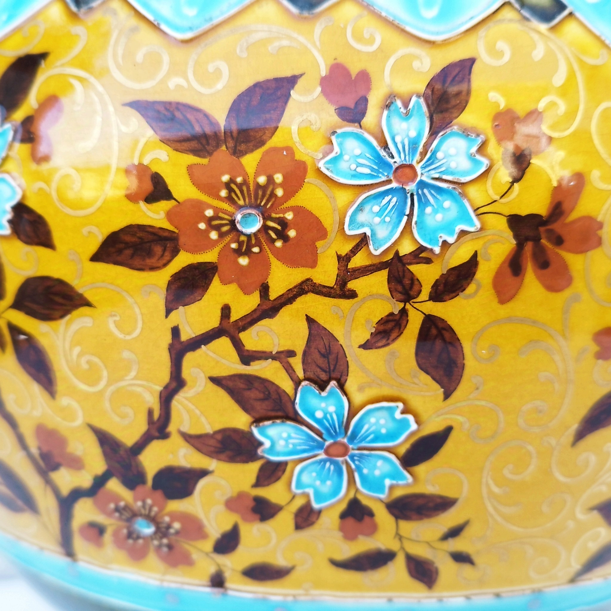 Grand cache-pot ou jardinière en céramique de Sarreguemines numéro 2048. Cerclé d'une couronne en bronze aux prises formant des lions. Pied tripodes en bronze. Couleurs bien vives. races d'usage à l'intérieur. Très bon état. Hauteur max  : 40 cm Diamètre : 25 cm