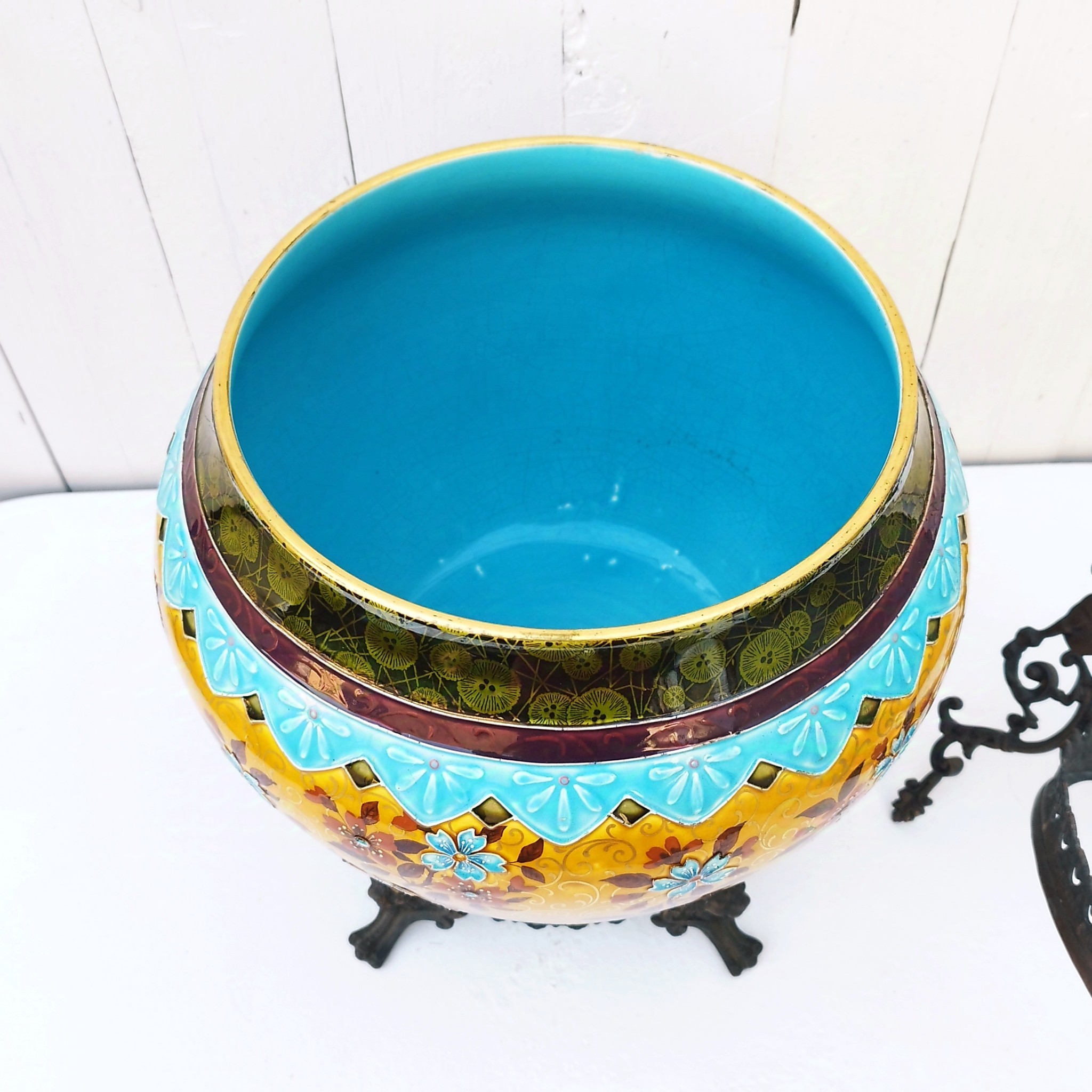 Grand cache-pot ou jardinière en céramique de Sarreguemines numéro 2048. Cerclé d'une couronne en bronze aux prises formant des lions. Pied tripodes en bronze. Couleurs bien vives. races d'usage à l'intérieur. Très bon état. Hauteur max  : 40 cm Diamètre : 25 cm