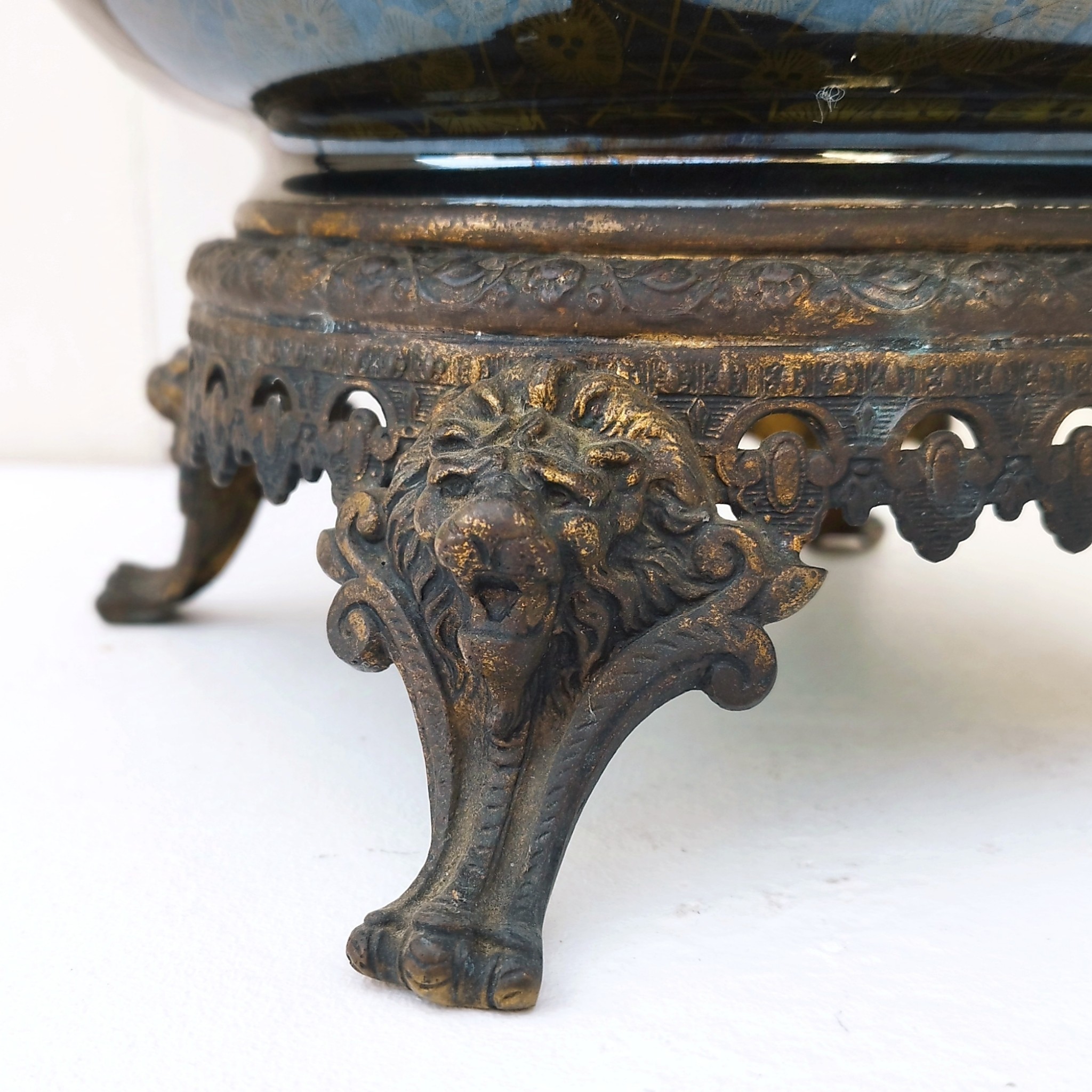 Grand cache-pot ou jardinière en céramique de Sarreguemines numéro 2048. Cerclé d'une couronne en bronze aux prises formant des lions. Pied tripodes en bronze. Couleurs bien vives. races d'usage à l'intérieur. Très bon état. Hauteur max  : 40 cm Diamètre : 25 cm