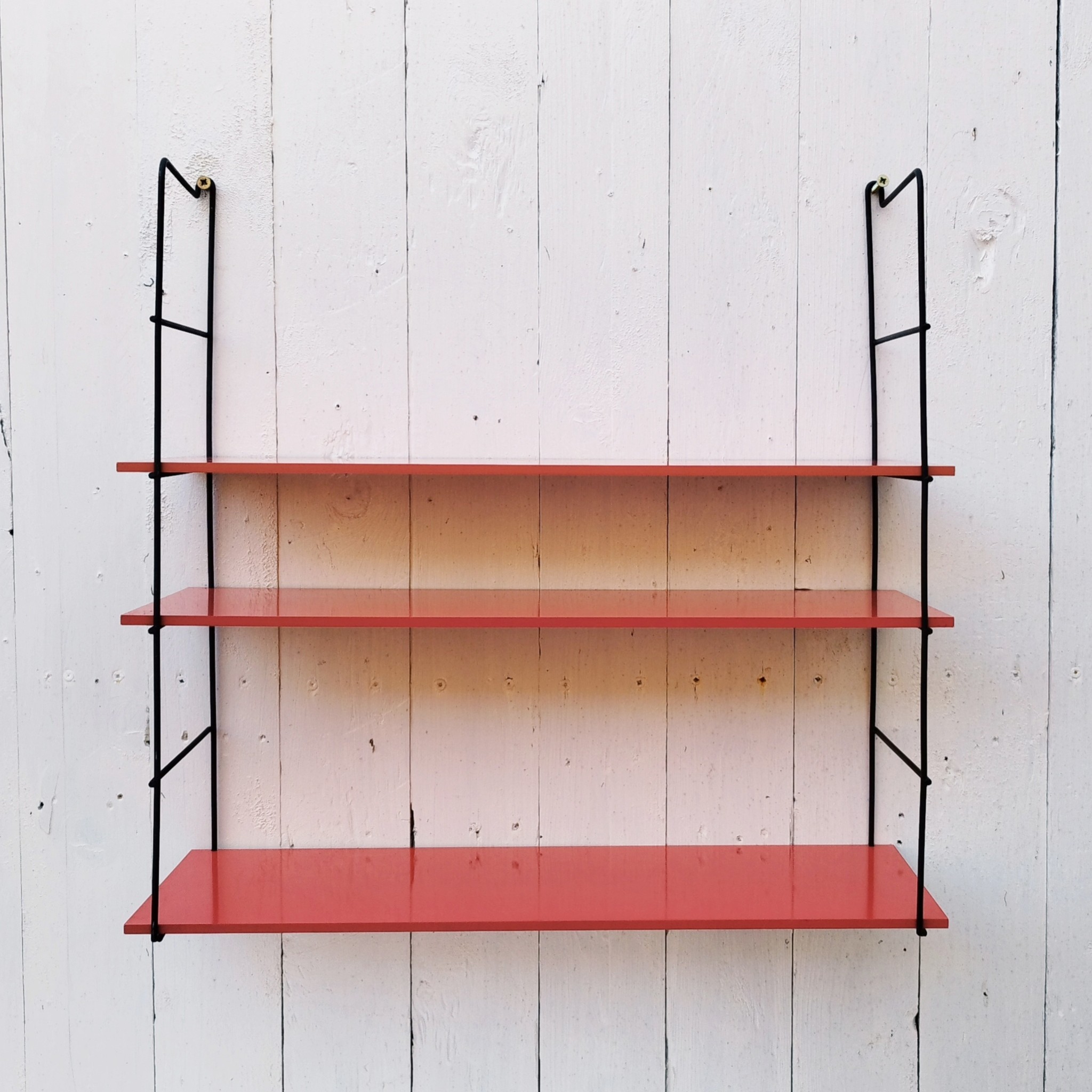 Etagère murale style string, montants en métal noir et étagères en mélaminé de couleur rouge. Petites rayures et taches sur les étagères, petites traces de corrosion sur les montants. Un montant légèrement tordu. Très bon état Hauteur : 52 cm Dimensions étagères : 52,5 x 17 cm