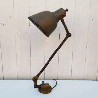 Lampe industrielle d’atelier datant des années 60. Deux bras articulés ( 34 cm et 11 cm). L'interrupteur d'origine sur le globe est HS mais électrification refaite avec interrupteur sur le fil. Traces de corrosion sur la lampe, des enfoncements sur le globe. Dans son jus Longueur max:  60 cm.