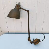 Lampe industrielle d’atelier datant des années 60. Deux bras articulés ( 34 cm et 11 cm). L'interrupteur d'origine sur le globe est HS mais électrification refaite avec interrupteur sur le fil. Traces de corrosion sur la lampe, des enfoncements sur le globe. Dans son jus Longueur max:  60 cm.
