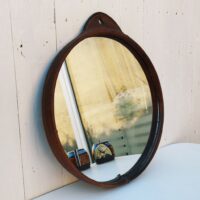 Miroir rond gainé de cuir, piqûre sellier sur l'attache , toile de jute de protection à l'arrière. Petites traces et rayures d'usage sur le miroir. Bon état général Diamètre : 35,5 cm