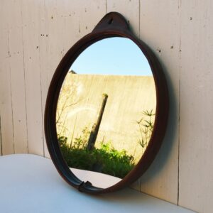 Miroir rond gainé de cuir, piqûre sellier sur l'attache , toile de jute de protection à l'arrière. Petites traces et rayures d'usage sur le miroir. Bon état général Diamètre : 35,5 cm