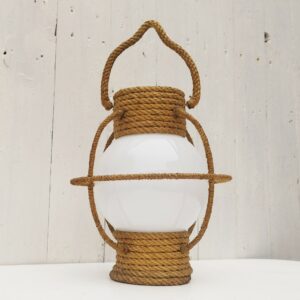 Suspension datant des années 50, à la forme d'une lanterne/lampe tempête créée par Audoux Minet. Structure en fil d'acier et métal recouvert de cordage tressé. Globe en opaline blanche. Manque sa douille à l'intérieur. Petit décollement de cordage sur le haut. Bon état général. Hauteur  avec anse: 36 cm