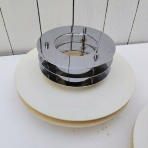 Paire d'appliques en métal blanc et chrome. Par l'italien Enrico Tronconi. Structure en lamelle de métal peinte en blanc rehaussé de trois lamelles plus petites en métal chromé. Jaunissure sur le métal blanc , des rayures sur les chromes. Idéales avec une ampoule argentée. Diamètre max : 25 cm Profondeur : 13 cm