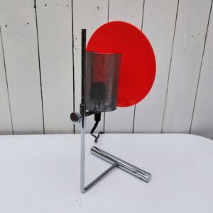 Lampe à poser datant des années 80-90 de l'enseigne Habitat. Structure en tube de métal chromé avec protège en grille perforée. Réflecteur en plastique rouge. Amovible de haut en bas grâce à la mollette sur l'arrière . Petites traces et rayures d'usage. Très bon état. Hauteur max : 48 cm Diamètre réflecteur : 17 cm