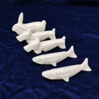 Cinq porte couteaux en porcelaine blanche représentant deux chiens , deux poisson et un lapin. Bon état général. Longueur : 10 cm