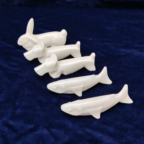 Cinq porte couteaux en porcelaine blanche représentant deux chiens , deux poisson et un lapin. Bon état général. Longueur : 10 cm