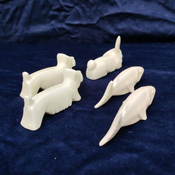 Cinq porte couteaux en porcelaine blanche représentant deux chiens , deux poisson et un lapin. Bon état général. Longueur : 10 cm