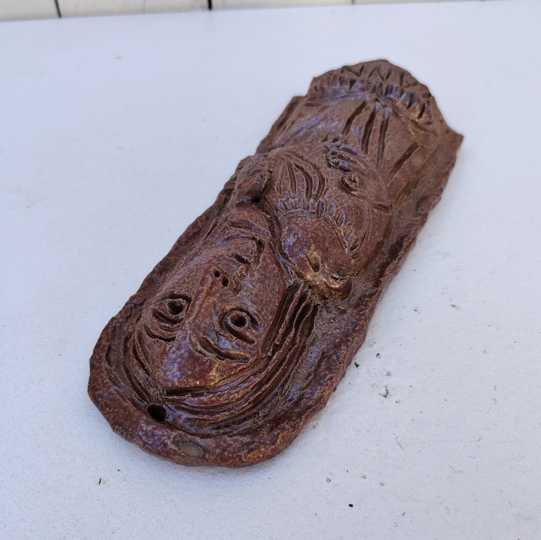 Sculpture anthropomorphe représenatnt Saint jean avec un oiseau en terre cuite vernisée, par Raymond Debiève. Un trou sur le haut pour l'accrocher au mur. Signé et daté en creux.