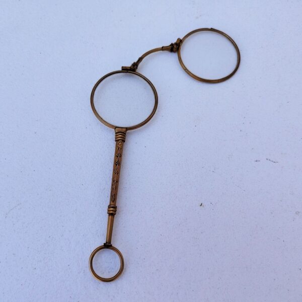 Lorgnette de théâtre pliante , en laiton doré, branche à décor ciselé. Petites rayures d'usage sur les verres. Bon état général . Longueur : 12,5 cm