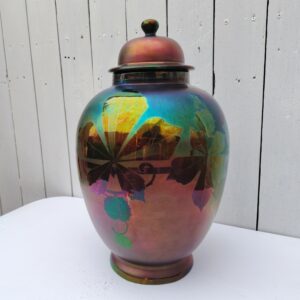 Grand pot couvert en céramique irisée , époque art déco. Décor de feuilles. Signé Montières. Quelques frottements. Très bon état. Hauteur avec couvercle : 41 cm Circonférence : 78  cm soit ( 25 cm de diamètre au plus large)