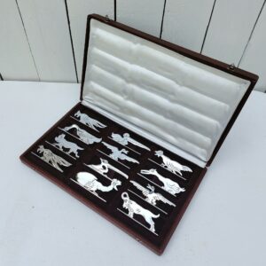 Boite de douze porte couteaux en métal argenté, à la forme d'animaux. Ils peuvent faire penser au travail de Benjamin Rabier. Boite d'origine. Petites traces d'usage. La charnière gauche est désolidarisé du couvercle, petits accrocs sur la boite Bon état général. Dimensions porte couteaux : 8 x 2,5 x 3,5 cm Dimensions boite : 31,5 x 19 x 4 cm
