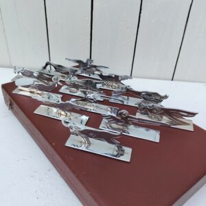 Boite de douze porte couteaux en métal argenté, à la forme d'animaux. Ils peuvent faire penser au travail de Benjamin Rabier. Boite d'origine. Petites traces d'usage. La charnière gauche est désolidarisé du couvercle, petits accrocs sur la boite Bon état général. Dimensions porte couteaux : 8 x 2,5 x 3,5 cm Dimensions boite : 31,5 x 19 x 4 cm