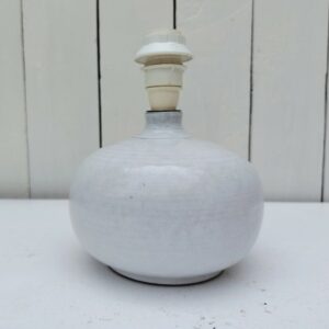 Lampe en céramique dans les tons gris clair, abat jour en raphia d'origine, signée en creux sur le dessous. Très bon état. Hauteur avec Abat-jour : 25 cm
