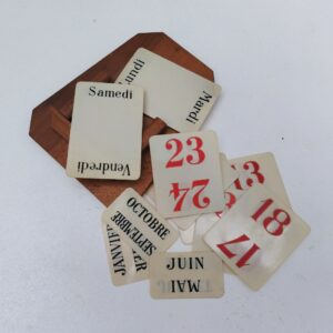 Calendrier perpétuel en bois et plaquettes des jours,mois et nombre en plastique. Datant des années 60. Petites rayures d'usage sur les plaquettes. Bon état général. Dimensions structure bois : 18 x 14 x 3,5 cm