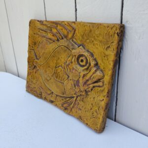 Carreau céramique par Goualc'h à Kerbigot en Bretagne. Représentant un poisson en relief. Décoration mural avec point d'accroche sur l'arrière. Un éclat sur le coin bas gauche. Signé en bas à gauche. Bon état général. Dimensions : 25 x 19 cm