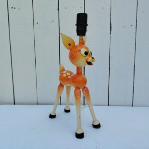 Pied de lampe datant des années 60, en bois peint à la forme de faon faisant penser à Bambi. Electrification d'origine, peinture écaillée. Bon état général Hauteur avec douille : 30 cm