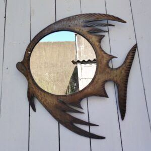 Miroir à la forme de poisson en feuille d'acier découpée et martelée pour former les écailles. Décoration vintage. Une nageoire sous la bouche est tordue. Bon état général Dimensions globales : 38 x 42 cm Diamètre miroir : 23 cm