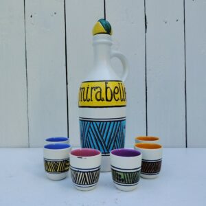 Service à liqueur mirabelle en céramique, par Elchinger datant des années 60, comprenant une bouteille et son bouchon à la forme de prune et de six verres à liqueur de différentes couleurs. Signé sur le dessous de la bouteille. Très bon état. Hauteur bouteille : 26,5 cm Hauteur et diamètre verre: 5 et 4 cm