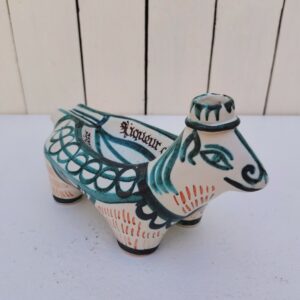 Bouteille et cendrier en céramique de la manufacture de Keraluc en Bretagne, par Toulhoat . Représentant une vache stylisée, marquée Liqueur du vieux presbytère . Signée sur le dessous. Manque son bouchon. *Bon état général. Dimensions : 21 x 11,5 x 13 cm