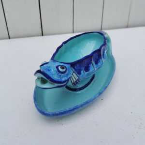 Saucière en faïence de Quimper à la forme de poisson, signée Henriot Quimper, VL pour Victor Lambertsur le dessous. Idéal pour pimper les tables d'été. Petites égrenures sur la gueule du poisson. Des petits défauts de cuisson Longueur : 23 cm Hauteur max : 9 cm