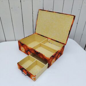    Boite à ouvrage ou couture datant des années 60-70 . Recouverte de tissu fleuri typique de cette époque. compartimentée en trois casiers à l'intérieur et d'un tiroir sur le devant Tâches intérieur sans gravité. Couleurs encore très fraîches. Déchirures de papier sur un des compartiments intérieur. Bon état général Longueur : 33 cm Largeur : 23 cm Hauteur : 10 cm