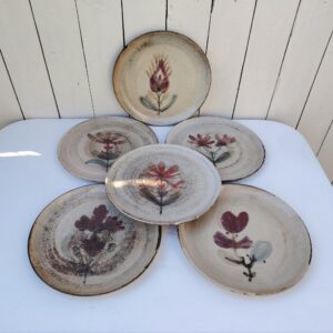 Six assiettes  plates en céramique, au décor de fleur, par Gustave Reynaud atelier le mûrier Vallauris. Elles ont toutes un décor différent et façonnées différemment. Excellent état. Diamètre : 24 cm