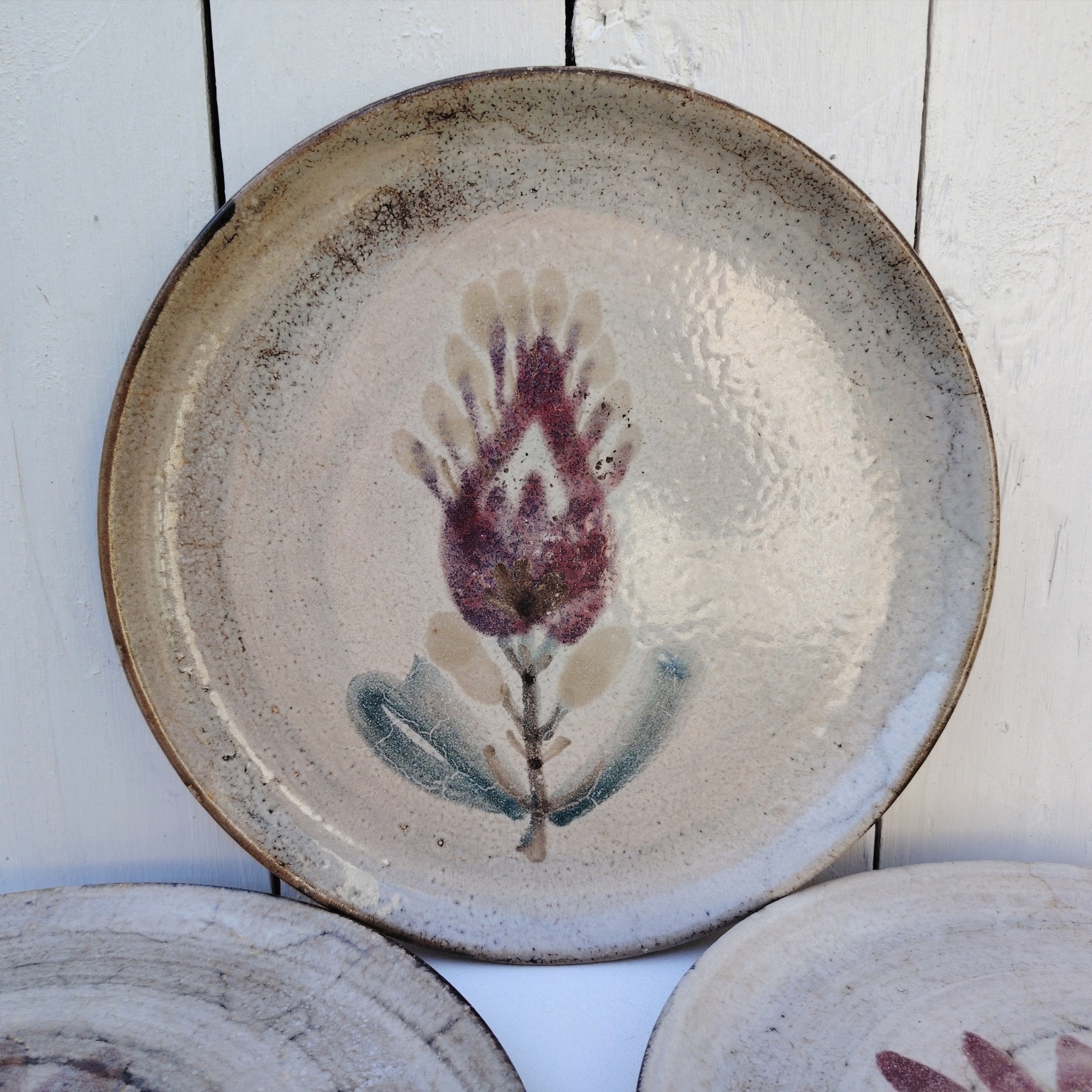 Six assiettes plates en céramique, au décor de fleur, par Gustave Reynaud atelier le mûrier Vallauris. Elles ont toutes un décor différent et façonnées différemment. Excellent état. Diamètre : 24 cm