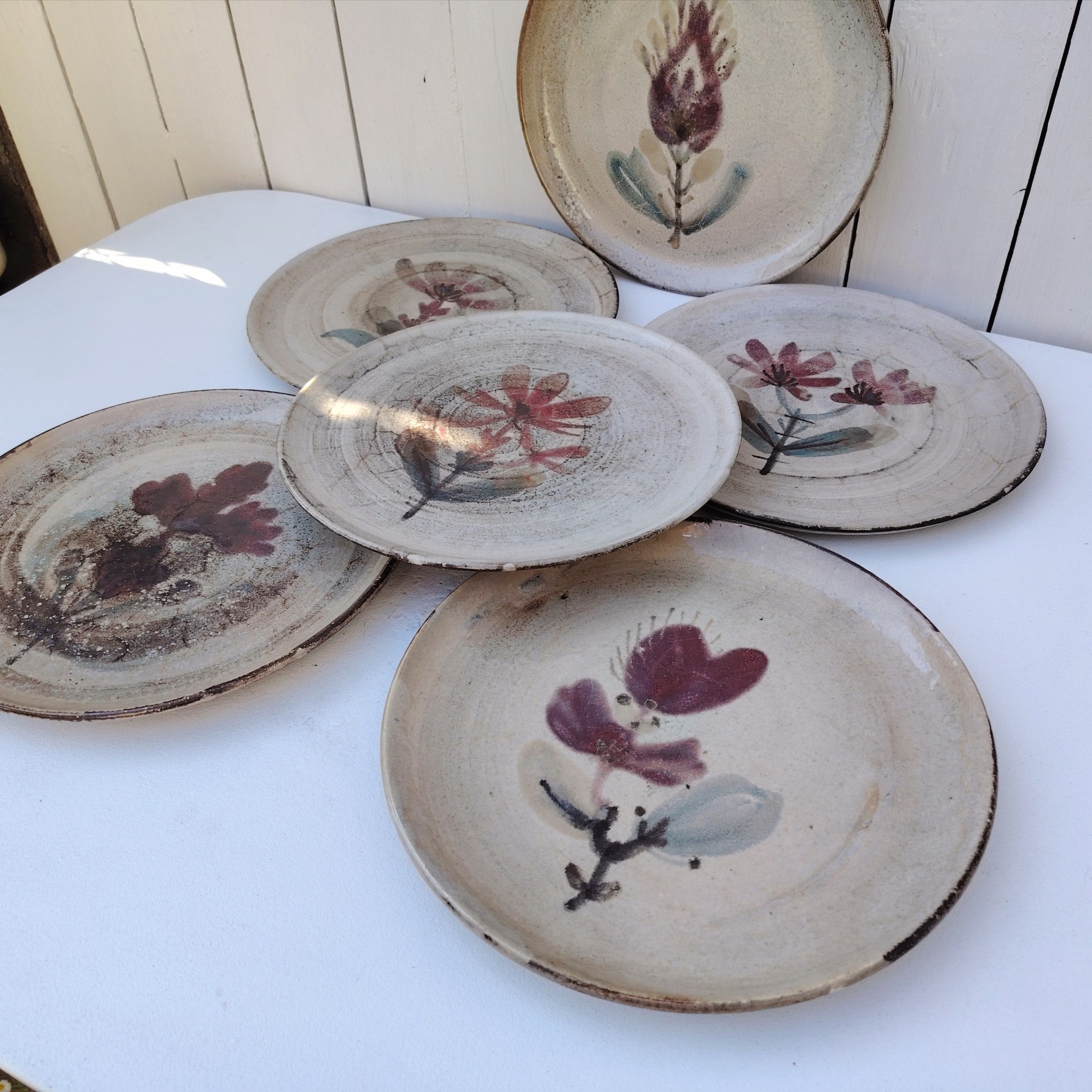 Six assiettes plates en céramique, au décor de fleur, par Gustave Reynaud atelier le mûrier Vallauris. Elles ont toutes un décor différent et façonnées différemment. Excellent état. Diamètre : 24 cm