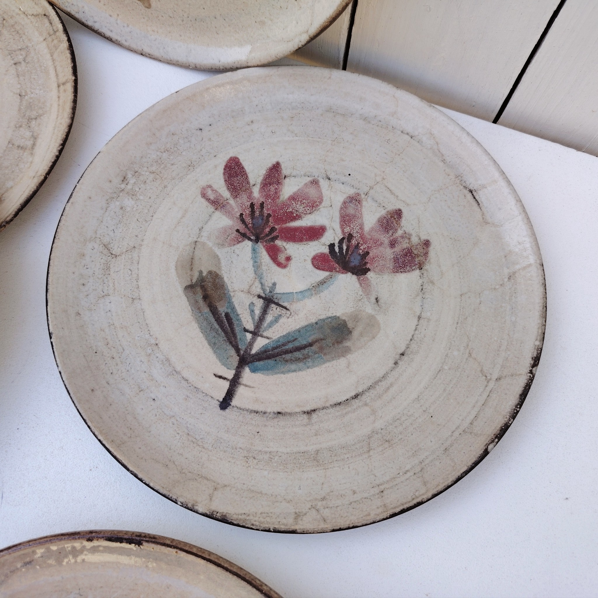 Six assiettes plates en céramique, au décor de fleur, par Gustave Reynaud atelier le mûrier Vallauris. Elles ont toutes un décor différent et façonnées différemment. Excellent état. Diamètre : 24 cm