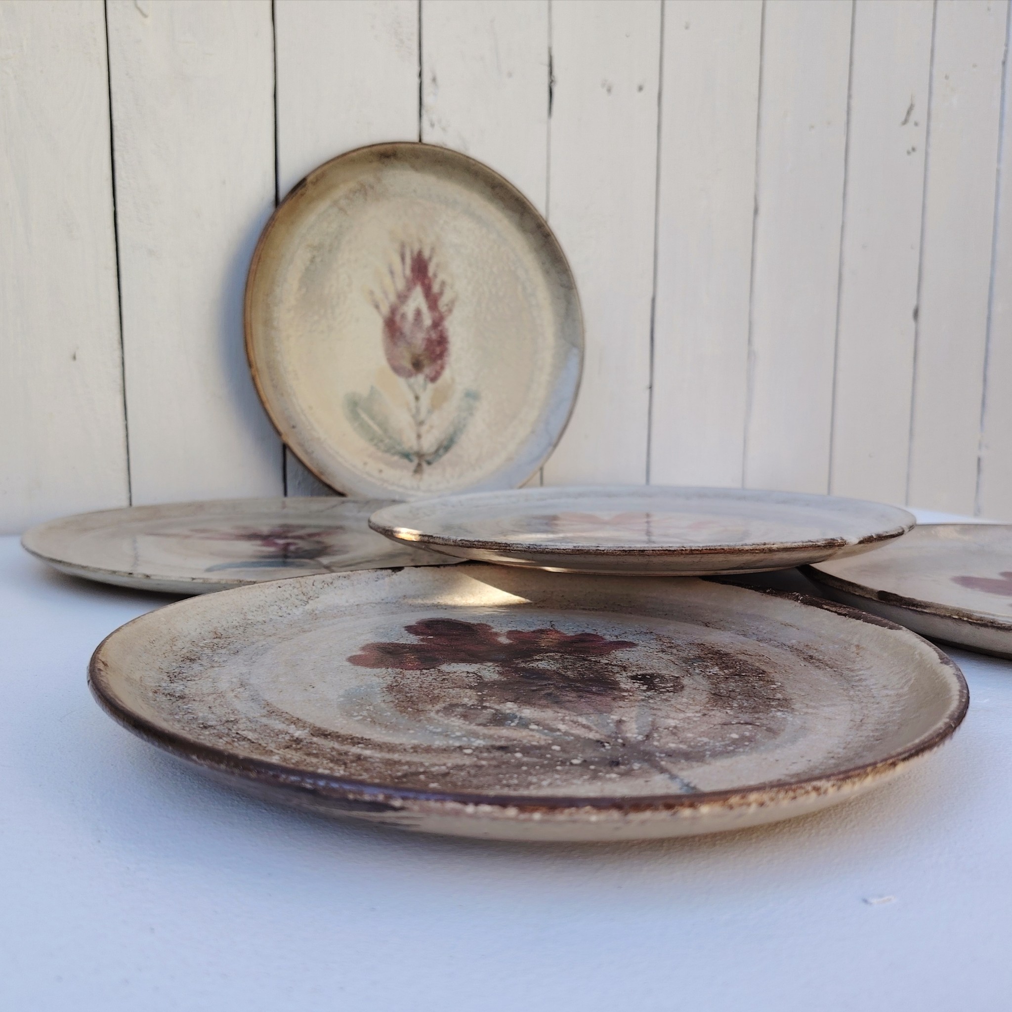Six assiettes plates en céramique, au décor de fleur, par Gustave Reynaud atelier le mûrier Vallauris. Elles ont toutes un décor différent et façonnées différemment. Excellent état. Diamètre : 24 cm