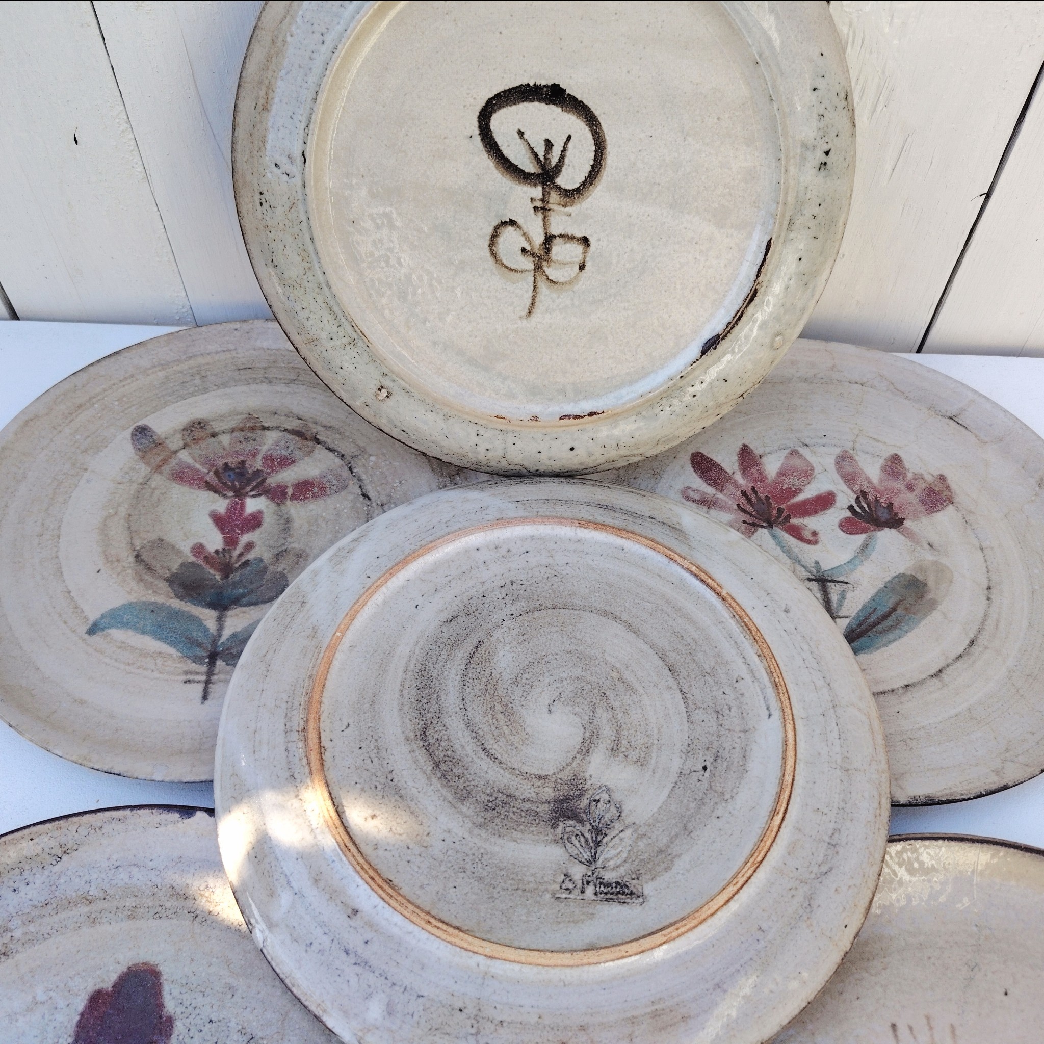 Six assiettes plates en céramique, au décor de fleur, par Gustave Reynaud atelier le mûrier Vallauris. Elles ont toutes un décor différent et façonnées différemment. Excellent état. Diamètre : 24 cm