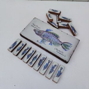 Dessous de plat et 16 porte-couteaux à décor de poisson,en céramique par Michel Boillot, Signé sur le dessous de plat Des petits éclats sur le contour du dessous de plat, petites égrenures sur les porte-couteaux  Bon état général. Dimensions dessous de plat : 25 x 12 cm Dimensions porte-couteau : 7 x 2 cm