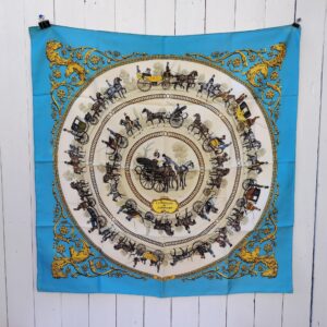 Foulard/carré Hermès intitulé : La promenade de Longchamps. En soie avec bords roulottés à la main. Des petites taches. Boite d'origine avec des manques sur le dessus, coins usés. Bon état général Dimensions : 90 x 90 cm