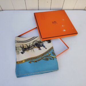 Foulard/carré Hermès intitulé : La promenade de Longchamps. En soie avec bords roulottés à la main. Des petites taches. Boite d'origine avec des manques sur le dessus, coins usés. Bon état général Dimensions : 90 x 90 cm