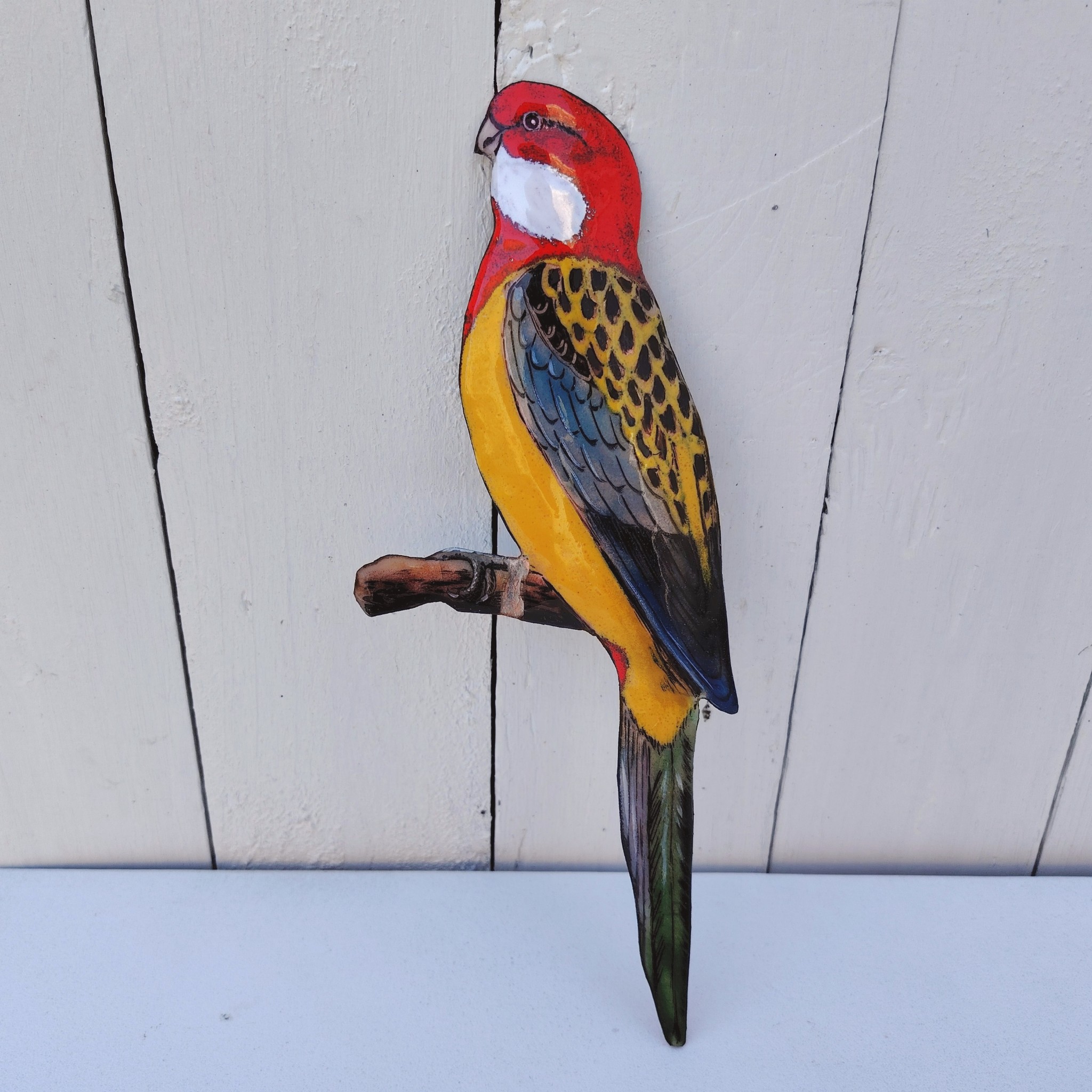 Oiseau représentant une perruche omnicolore, en émaux de Limoges sur cuivre. Datant des années 60-70. .Ne possède pas de point d'accroche. Un éclat sur la branche. Branche légèrement tordue Bon état général. Dimensions : 26 x 10 cm