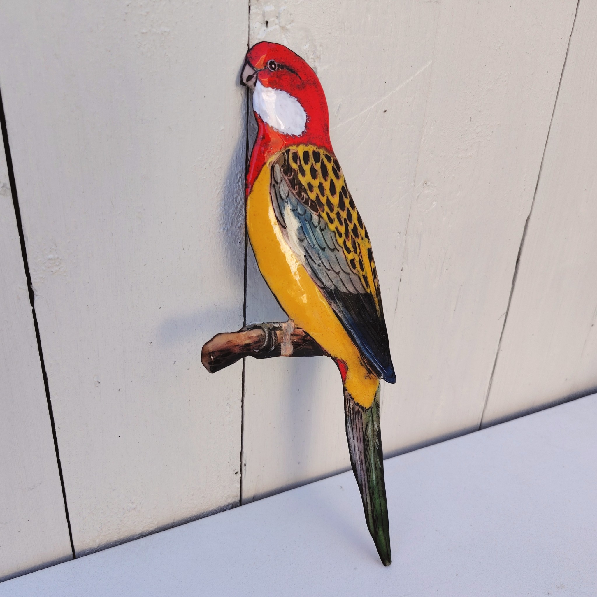 Oiseau représentant une perruche omnicolore, en émaux de Limoges sur cuivre. Datant des années 60-70. .Ne possède pas de point d'accroche. Un éclat sur la branche. Branche légèrement tordue Bon état général. Dimensions : 26 x 10 cm