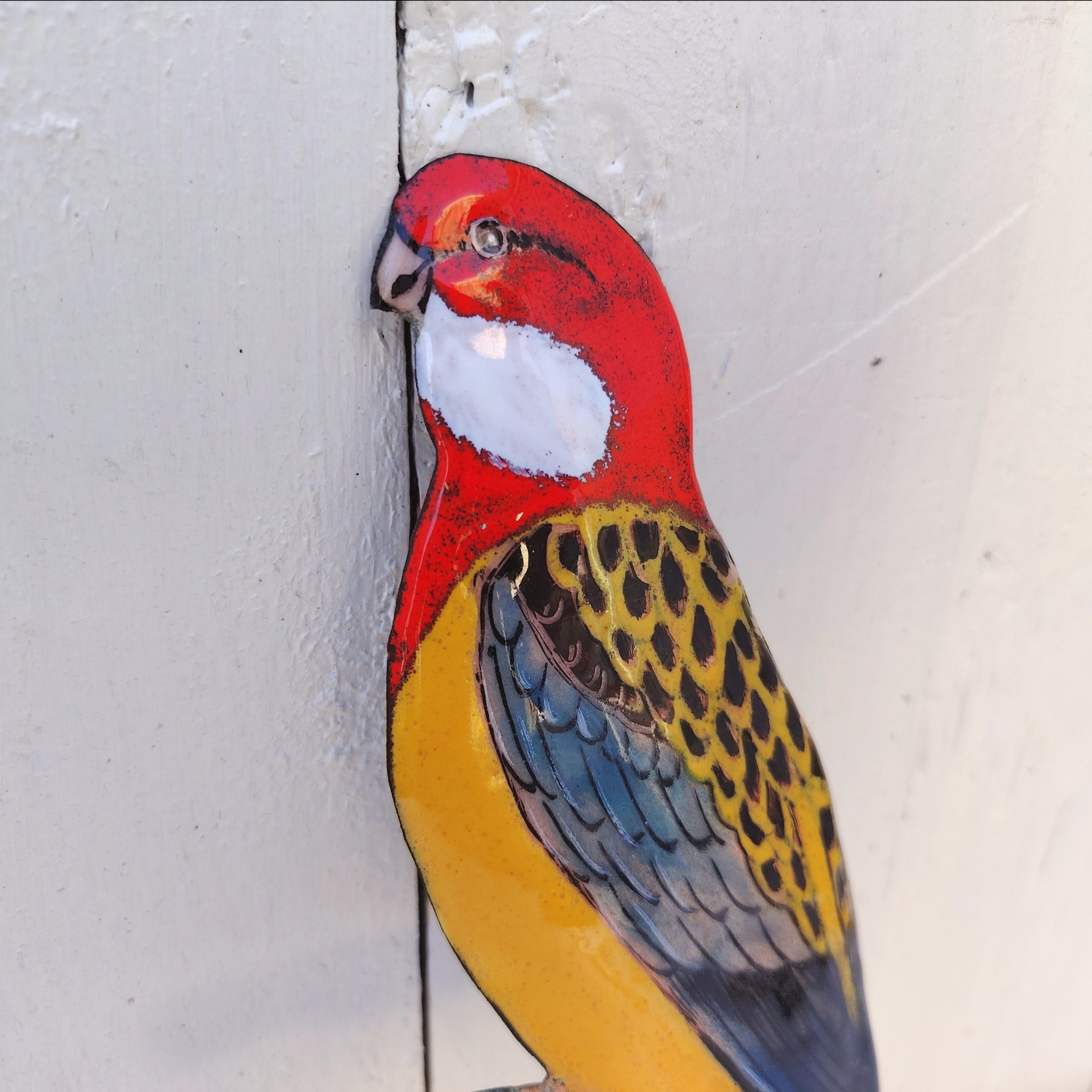 Oiseau représentant une perruche omnicolore, en émaux de Limoges sur cuivre. Datant des années 60-70. .Ne possède pas de point d'accroche. Un éclat sur la branche. Branche légèrement tordue Bon état général. Dimensions : 26 x 10 cm