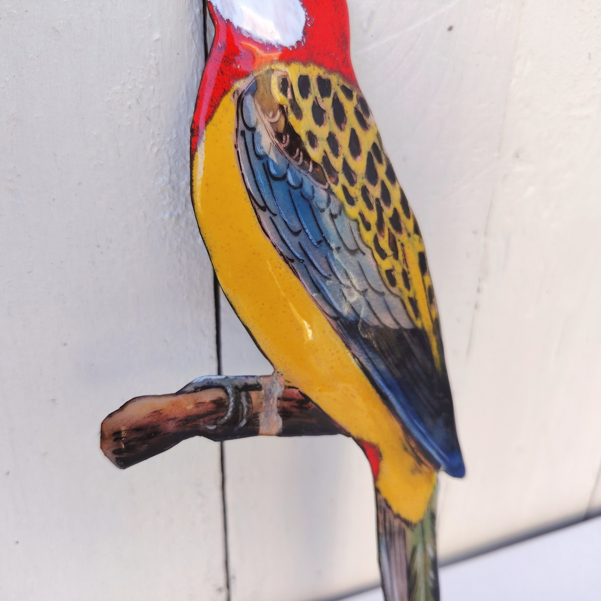 Oiseau représentant une perruche omnicolore, en émaux de Limoges sur cuivre. Datant des années 60-70. .Ne possède pas de point d'accroche. Un éclat sur la branche. Branche légèrement tordue Bon état général. Dimensions : 26 x 10 cm