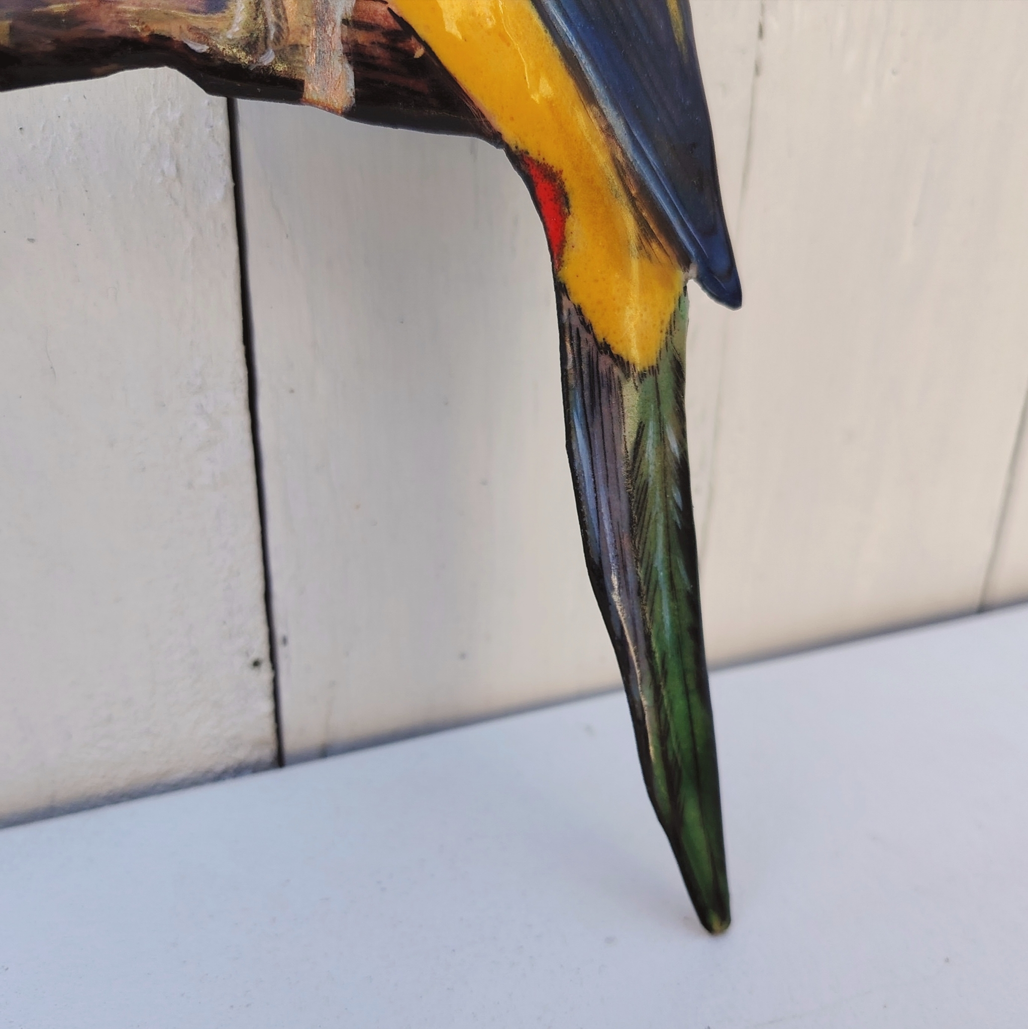 Oiseau représentant une perruche omnicolore, en émaux de Limoges sur cuivre. Datant des années 60-70. .Ne possède pas de point d'accroche. Un éclat sur la branche. Branche légèrement tordue Bon état général. Dimensions : 26 x 10 cm