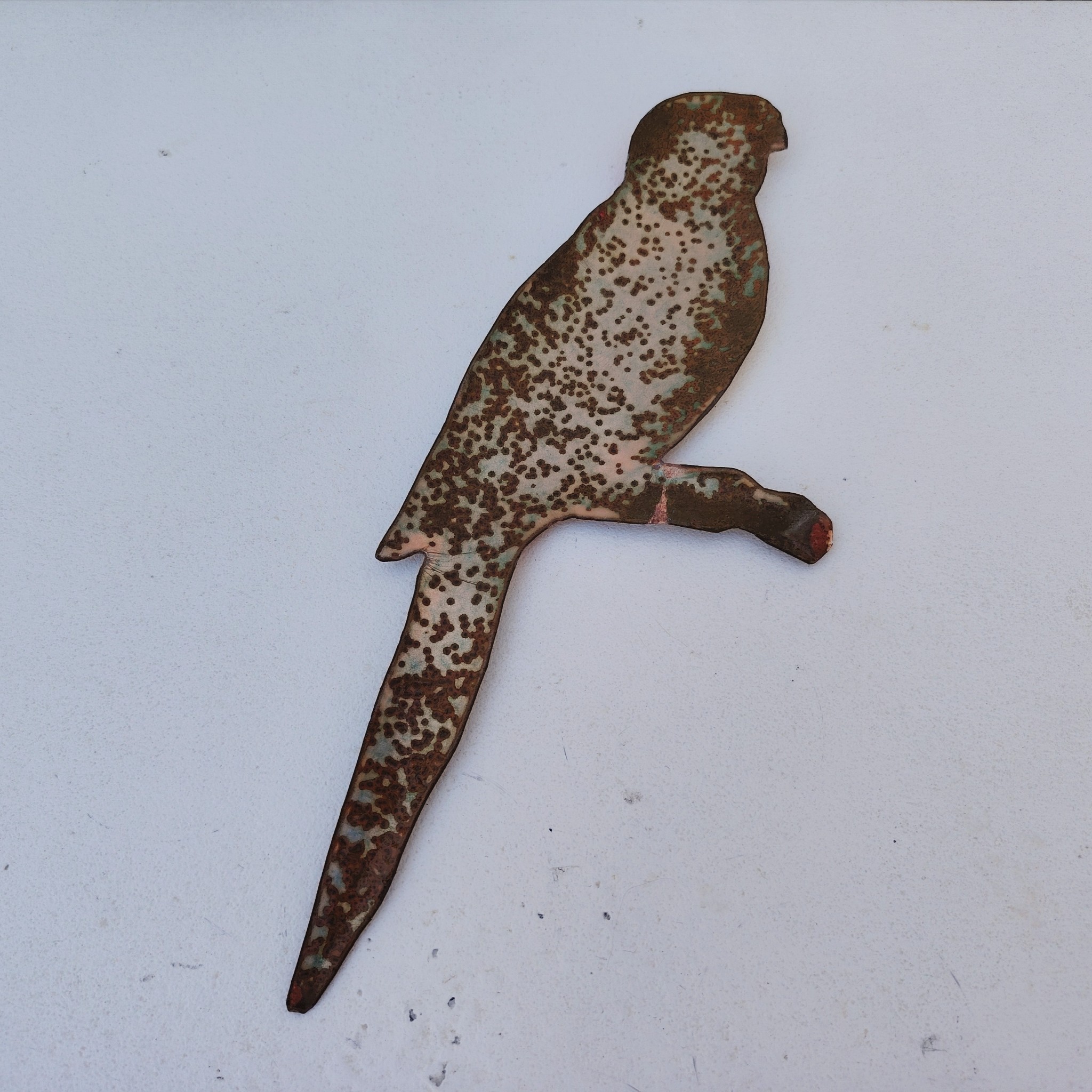 Oiseau représentant une perruche omnicolore, en émaux de Limoges sur cuivre. Datant des années 60-70. .Ne possède pas de point d'accroche. Un éclat sur la branche. Branche légèrement tordue Bon état général. Dimensions : 26 x 10 cm