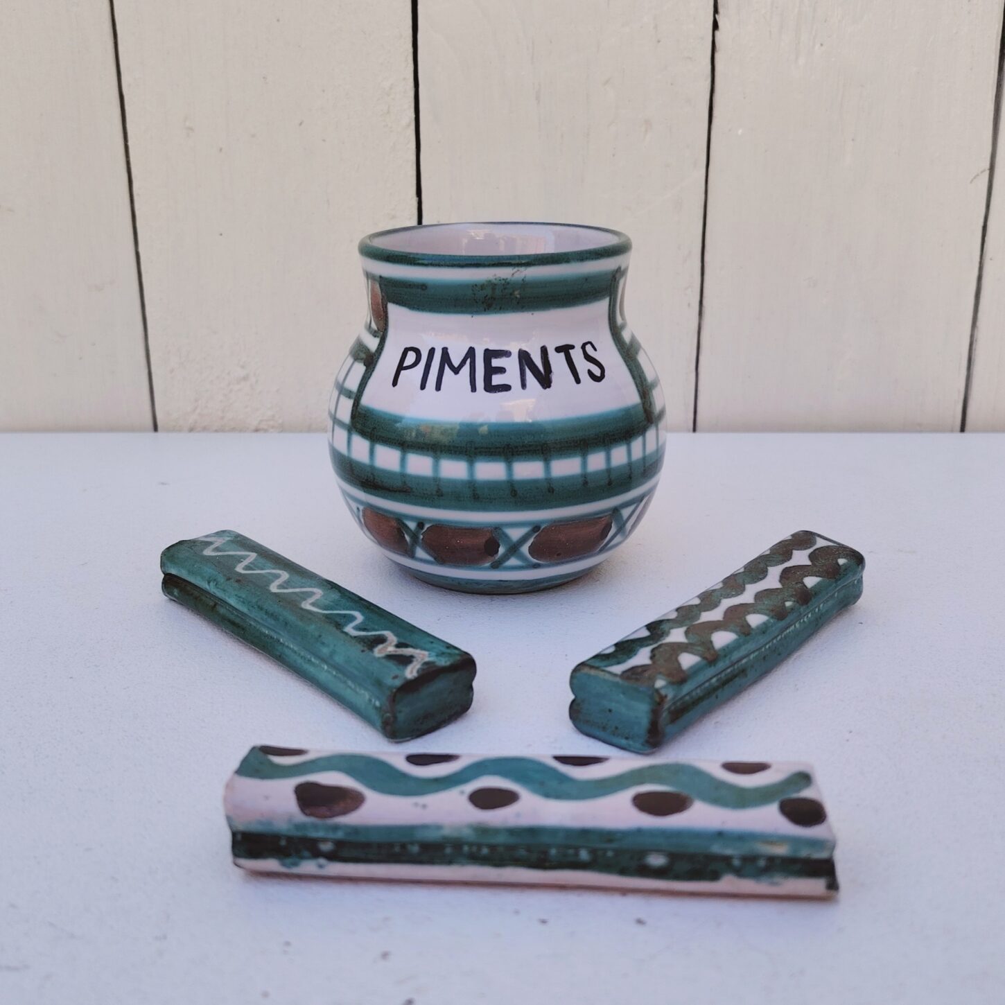 Lot en céramique de Vallauris par Robert Picault comprenant un pot à piments et trois porte-couteaux. Datant des années 60. Petites égrenures sur les coins des porte-couteaux sans gravité. Longueur porte-couteaux : 9 cm hauteur pot : 8,5 cm Diamètre : 6 cm
