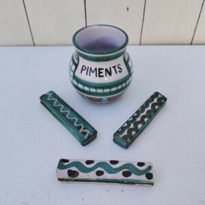 Lot en céramique de Vallauris par Robert Picault comprenant un pot à piments et trois porte-couteaux. Datant des années 60. Petites égrenures sur les coins des porte-couteaux sans gravité. Longueur porte-couteaux : 9 cm hauteur pot : 8,5 cm Diamètre : 6 cm